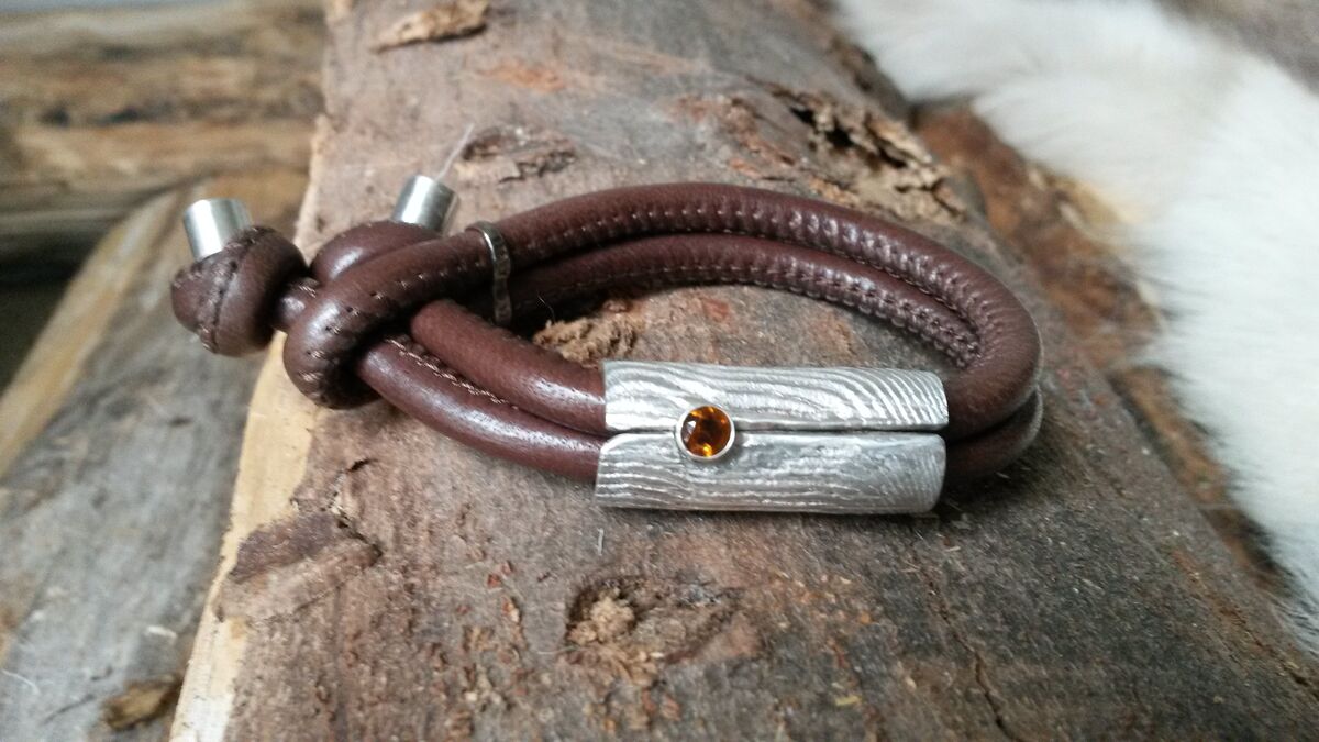 Bruine leren armband met een zilveren ornament en een oranje steentje